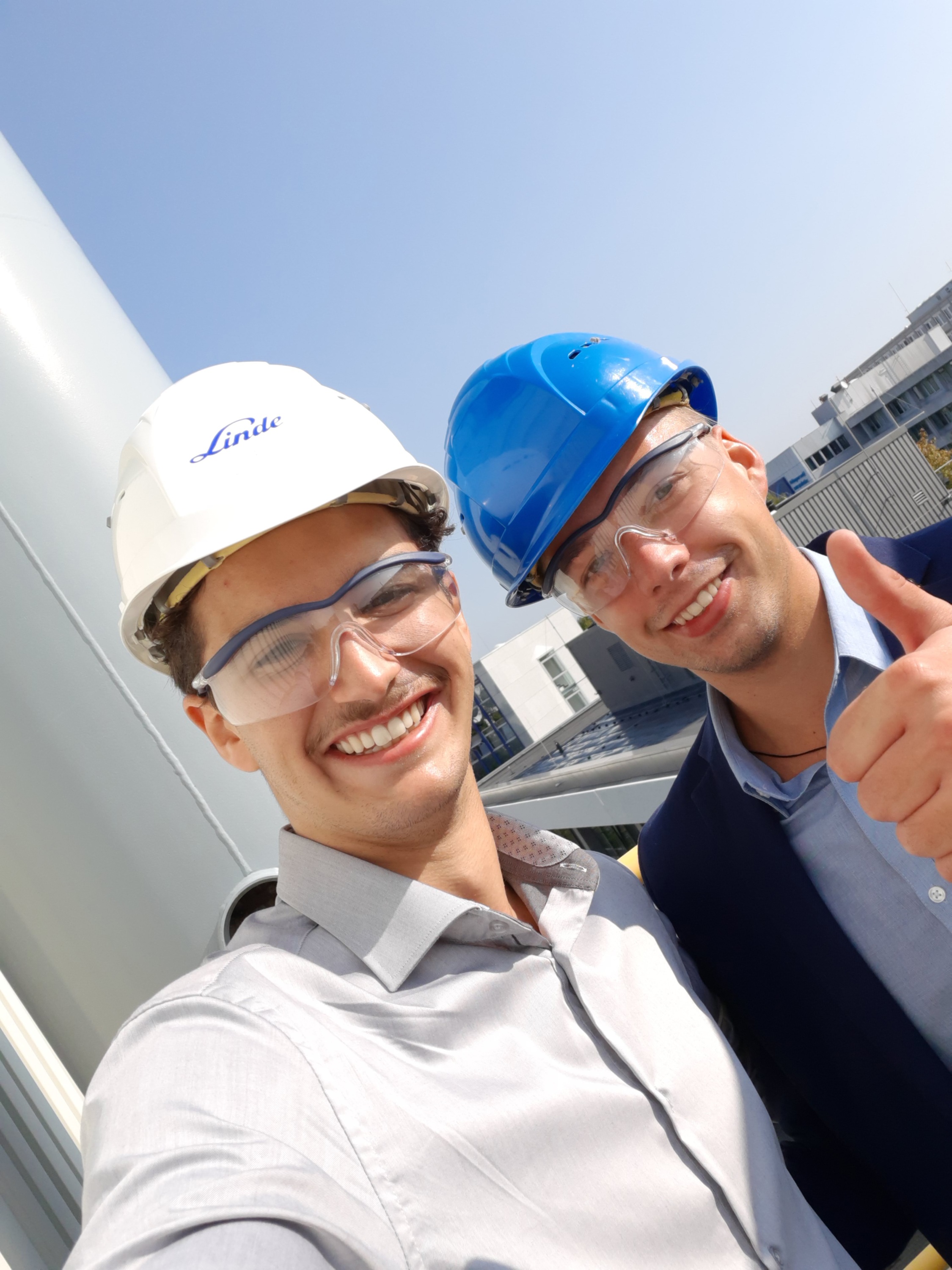 Zwei Ingenieurstudenten mit Schutzhelmen zeigen den Daumen hoch.