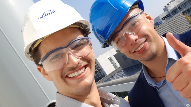 Zwei Ingenieurstudenten mit Schutzhelmen zeigen den Daumen hoch.