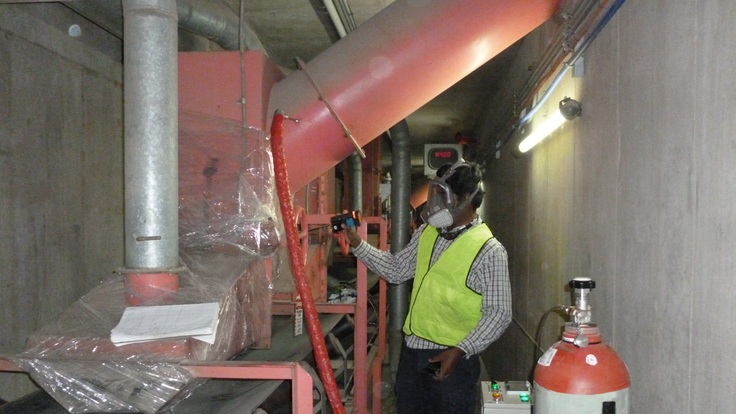 An operator dressed in PPE carries out a fumigation in an enclosed space.