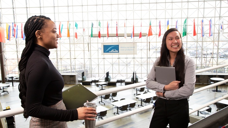 "Two female employees smiling in conversation."
