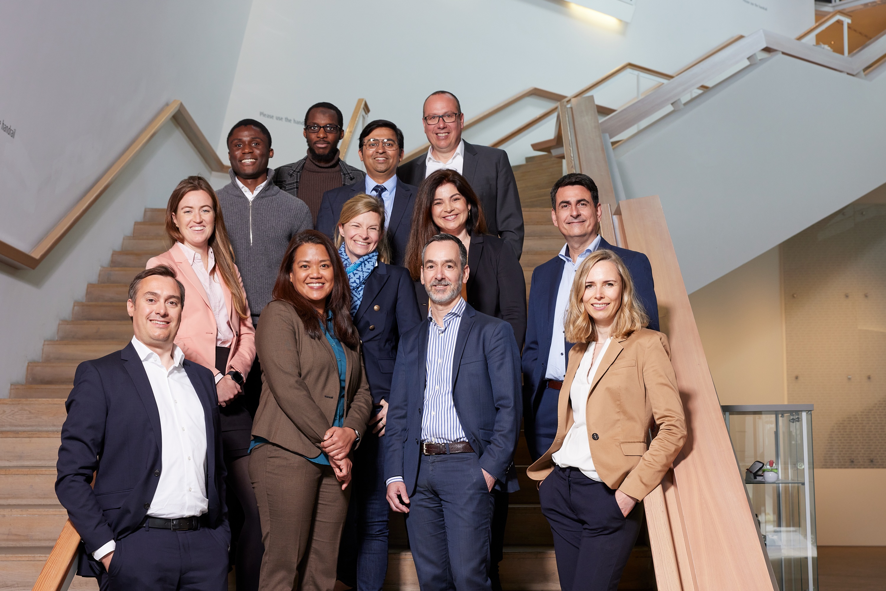 "Group photo of twelve Linde employees in smart business attire facing the camera arranged on a staircase."