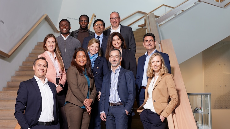 "Group photo of twelve Linde employees in smart business attire facing the camera arranged on a staircase."