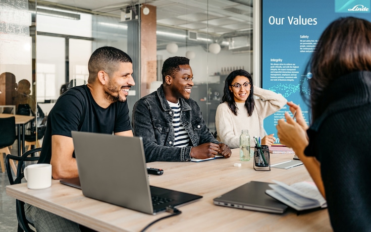 Group of diverse businesspeople laughing and smiling during a meeting in modern workplace.