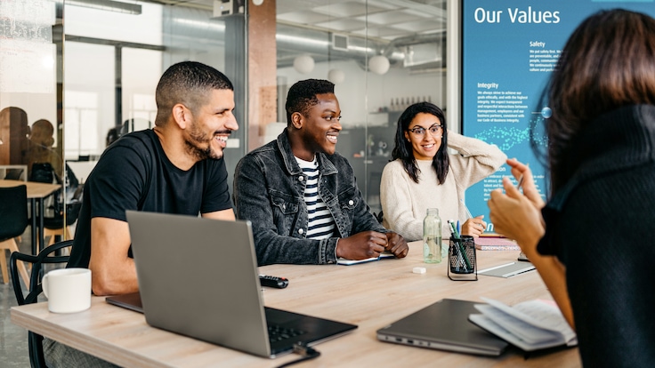Group of diverse businesspeople laughing and smiling during a meeting in modern workplace.