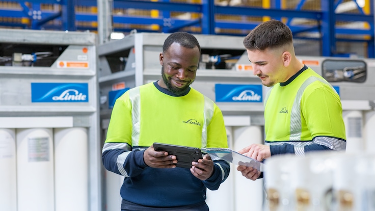 Zwei Lagertechniker schauen auf ein Tablet-Gerät.