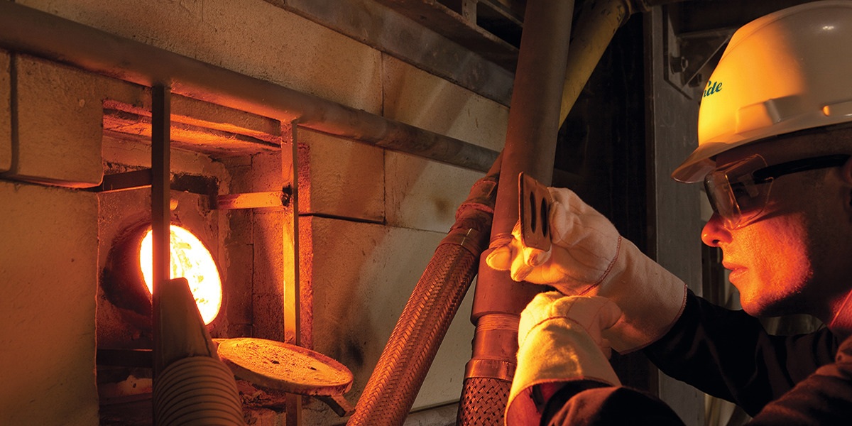 A worker checking flame in glass furnace