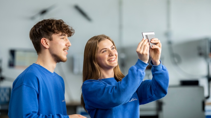 Junge Industriemechaniker überprüfen etwas an einer Maschine.