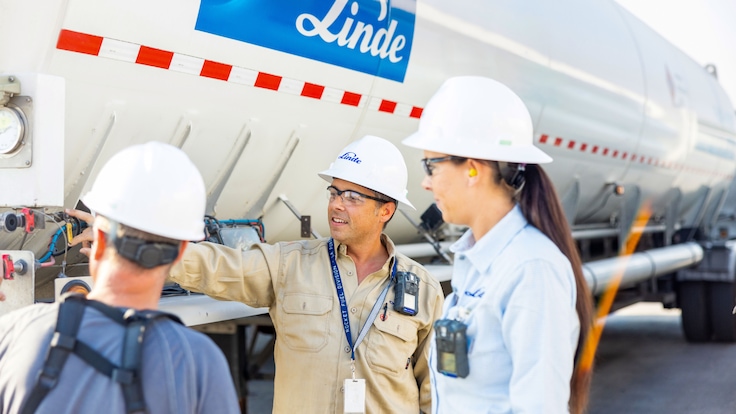 Three people talking in front of a truck