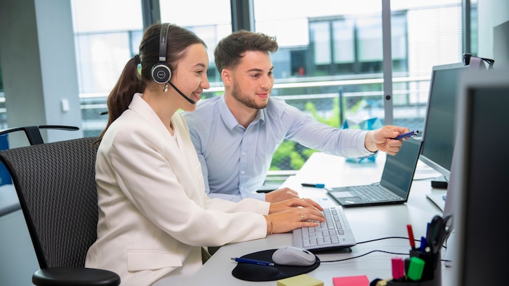 Female clerk works at desk wearing headset.