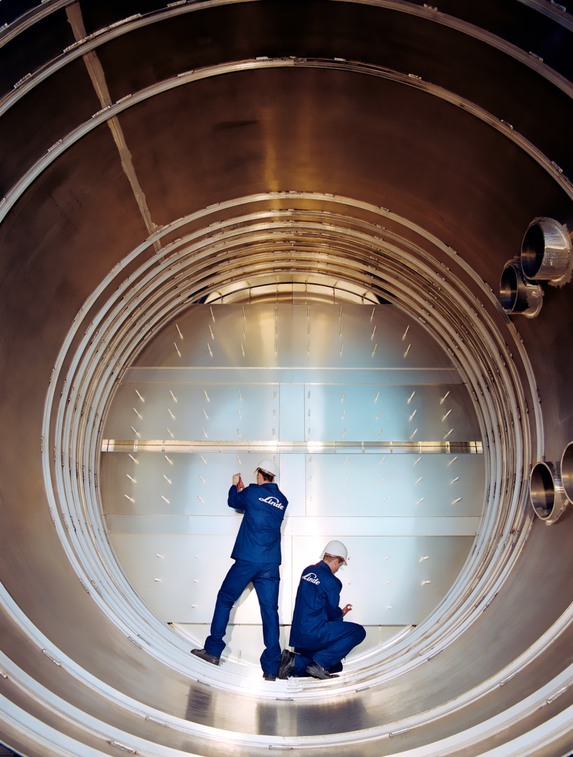 Men are working at sieve tray column, Schalchen, Germany.