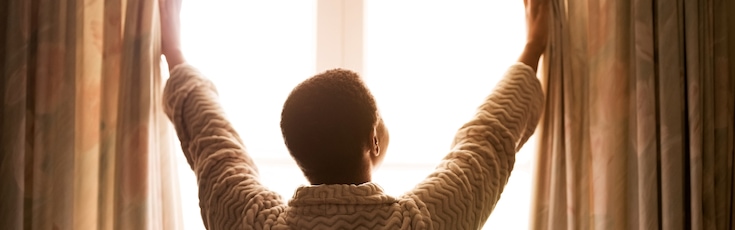 femme ouvrant les rideaux le matin