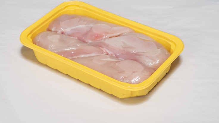 Packaged meat in a yellow plastic tray