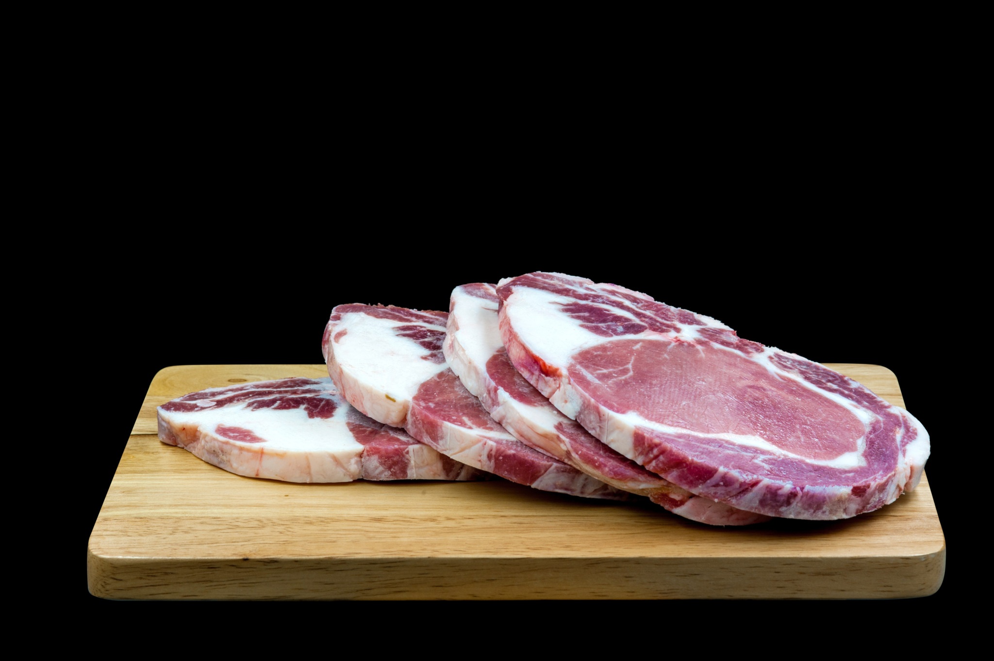 Sliced raw steak sitting on a wooden chopping board