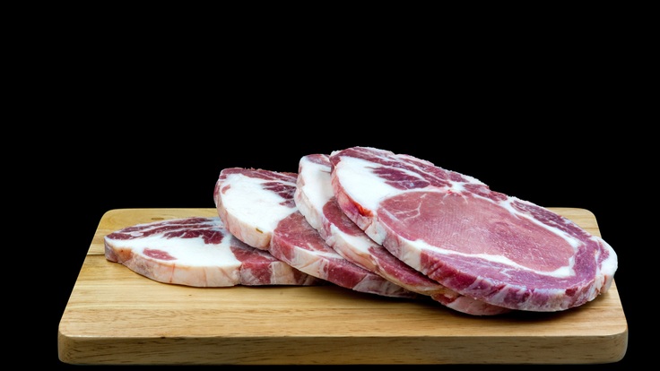Sliced raw steak sitting on a wooden chopping board