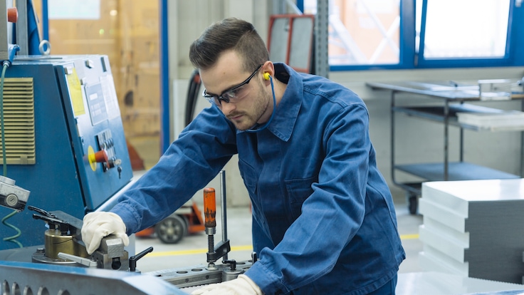 Junger Auszubildender arbeitet mit Metall