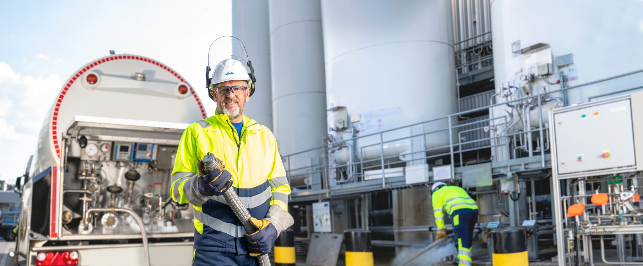 Arbeiter mit Helm steht vor einem LKW