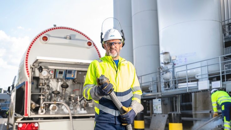 Arbeiter mit Helm steht vor einem LKW