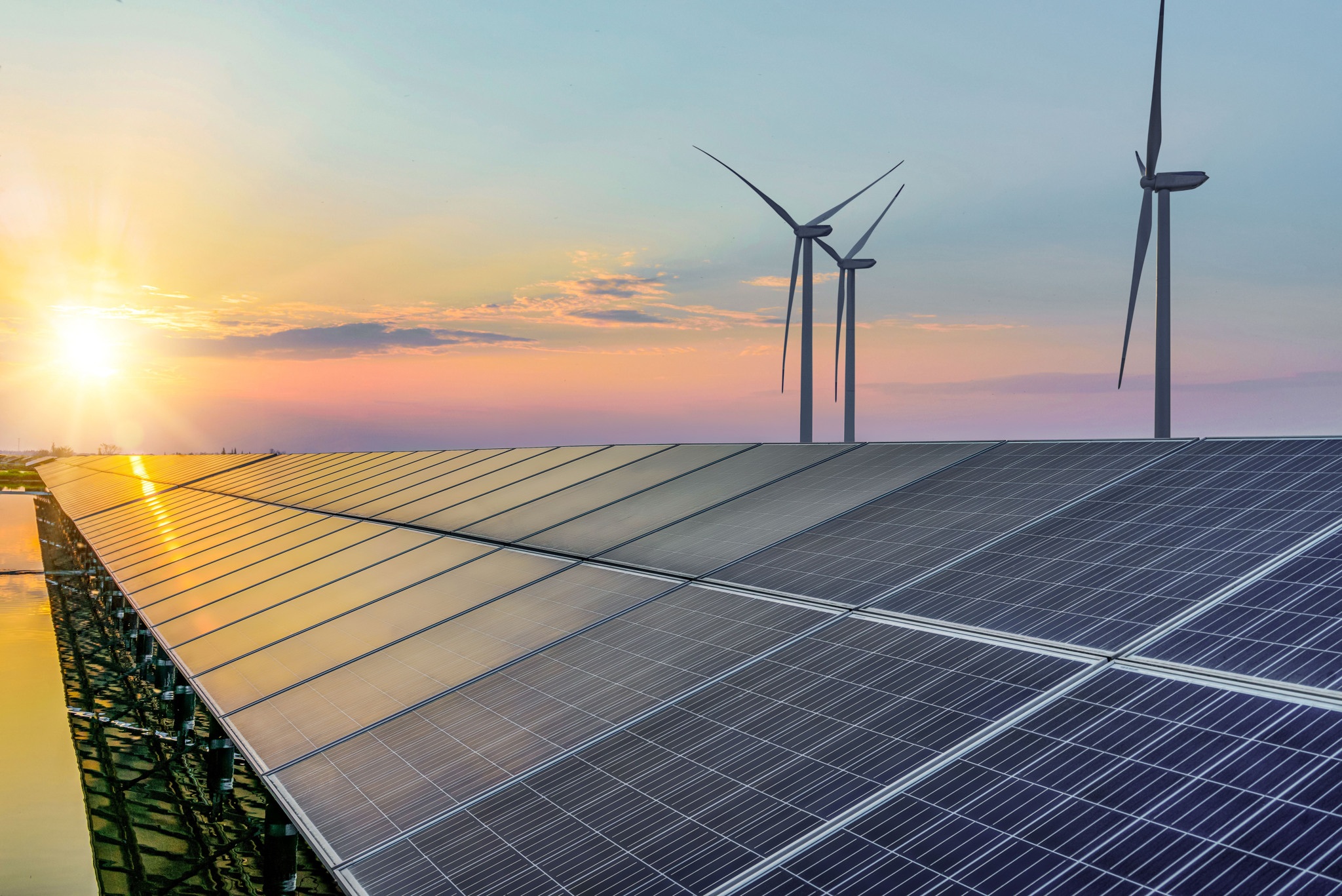 Solar panels and wind turbines against a sunrise