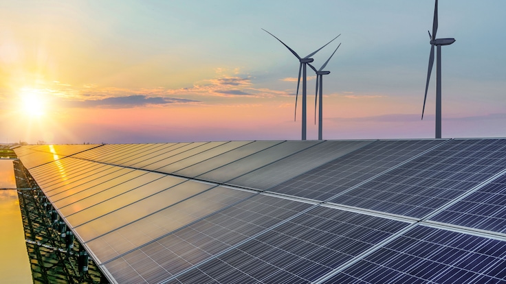 Solar panels and wind turbines against a sunrise