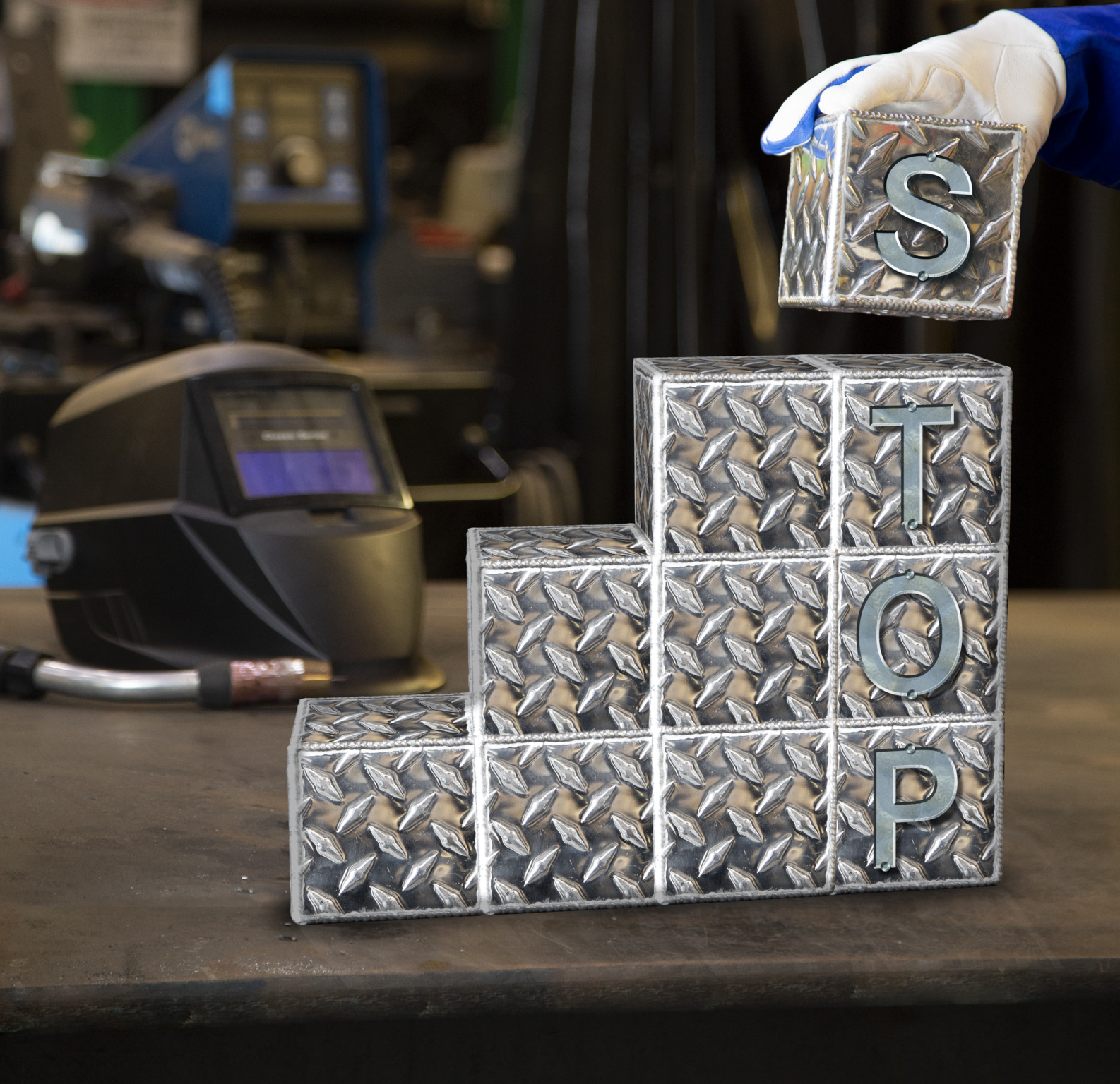 Metallic, welded cubes visualize the S.T.O.P hierarchy of controls recommended for OSH in welding.